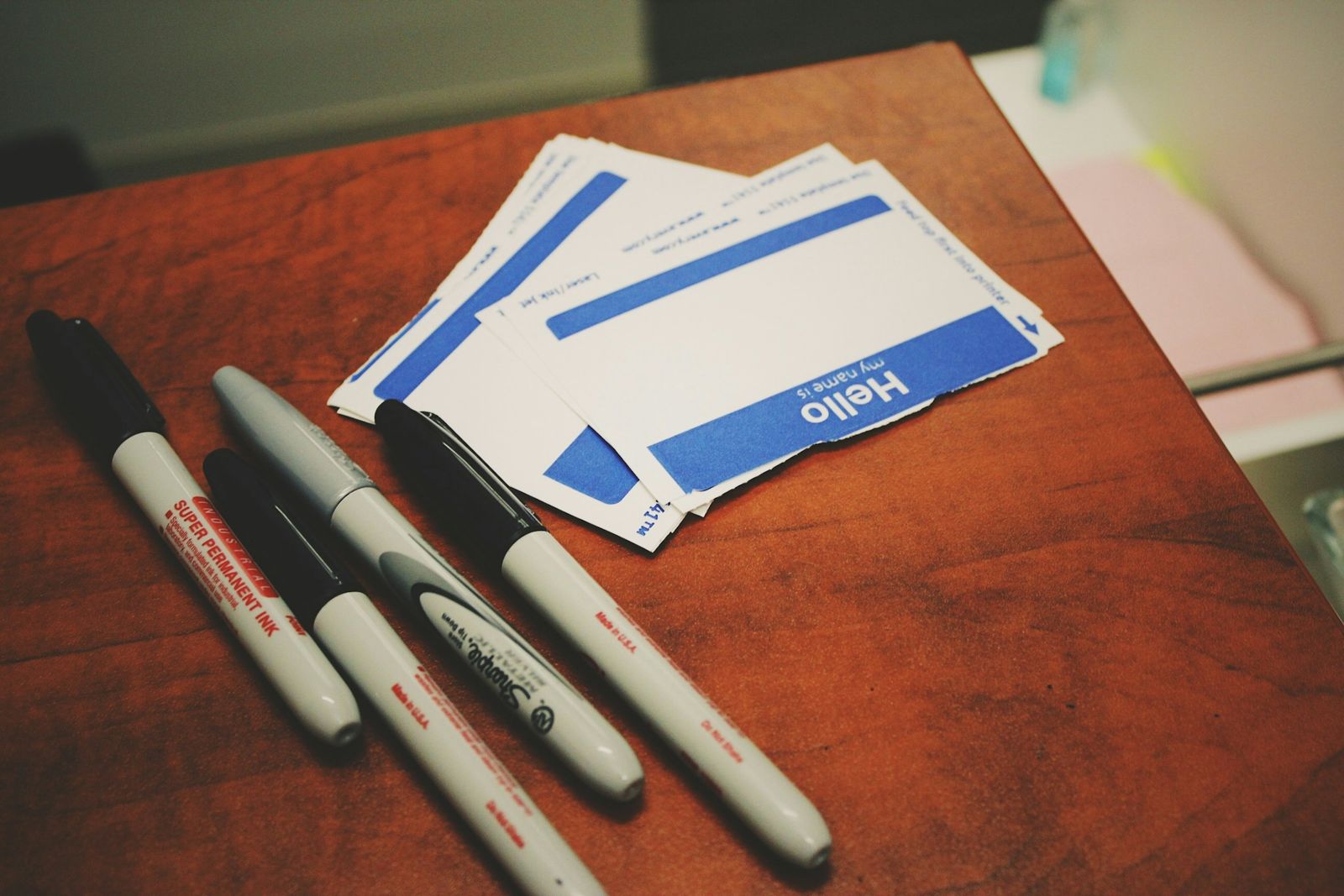 Blank hello name badges with marker pens on a wooden table